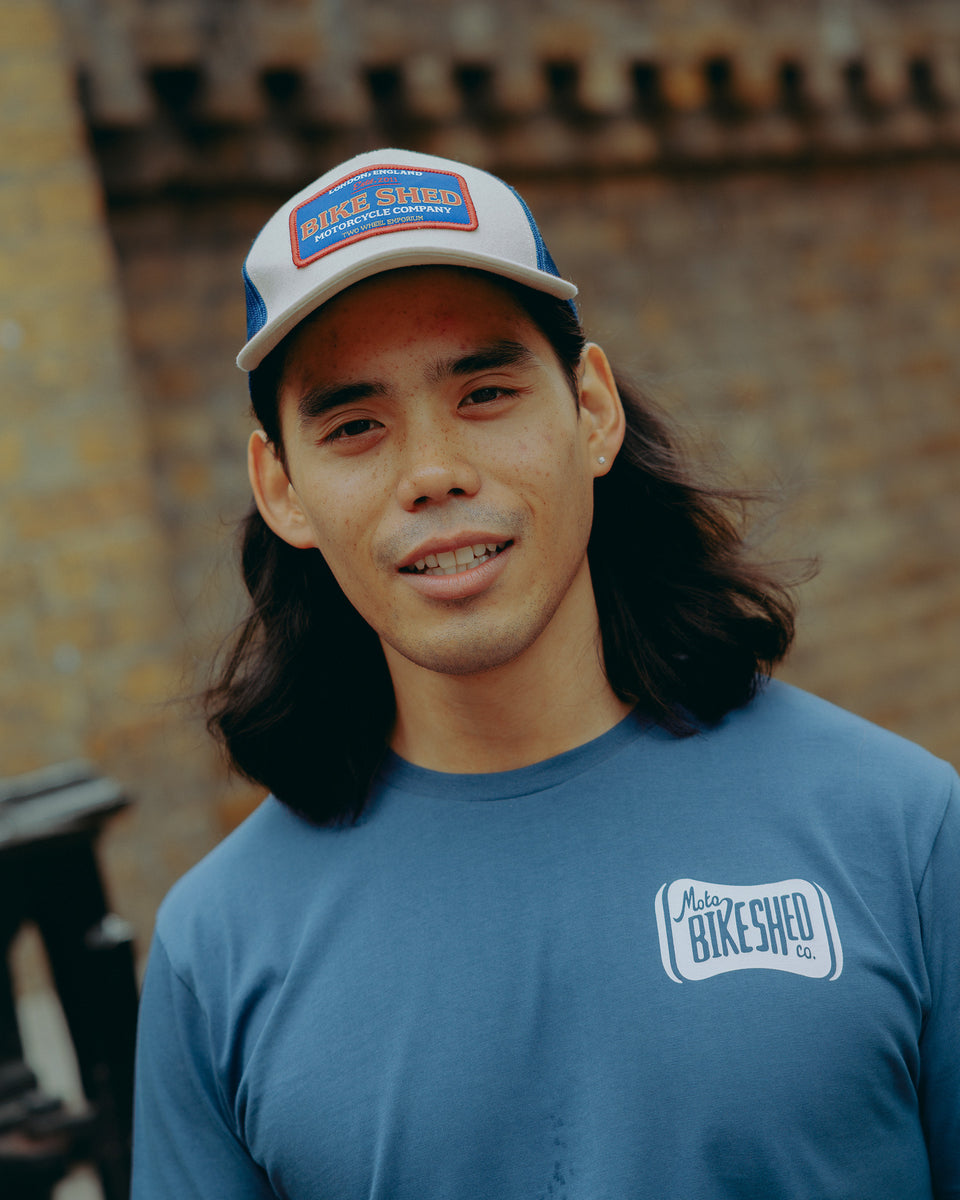 Model wearing navy blue t-shirt with 'Moto Bikeshed co'  logo - front