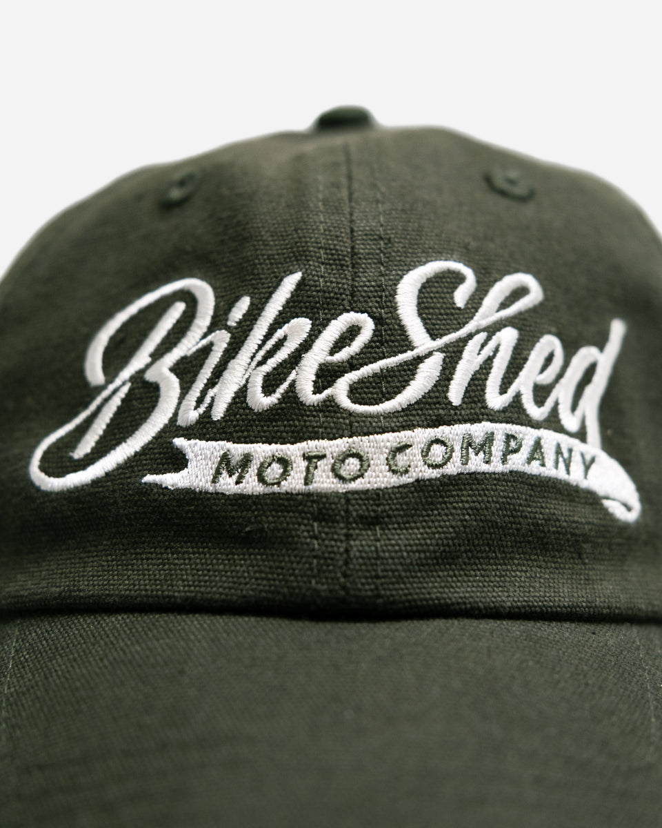 Green cap studio shot with 'Bike Shed Moto Company' logo on a white background