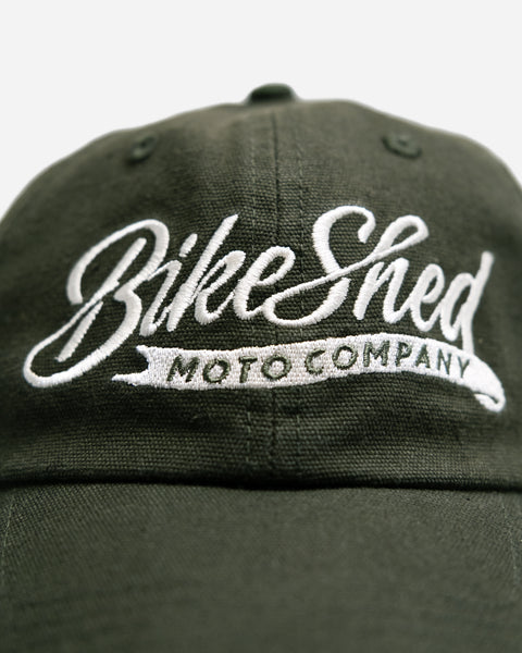 Green cap studio shot with 'Bike Shed Moto Company' logo on a white background
