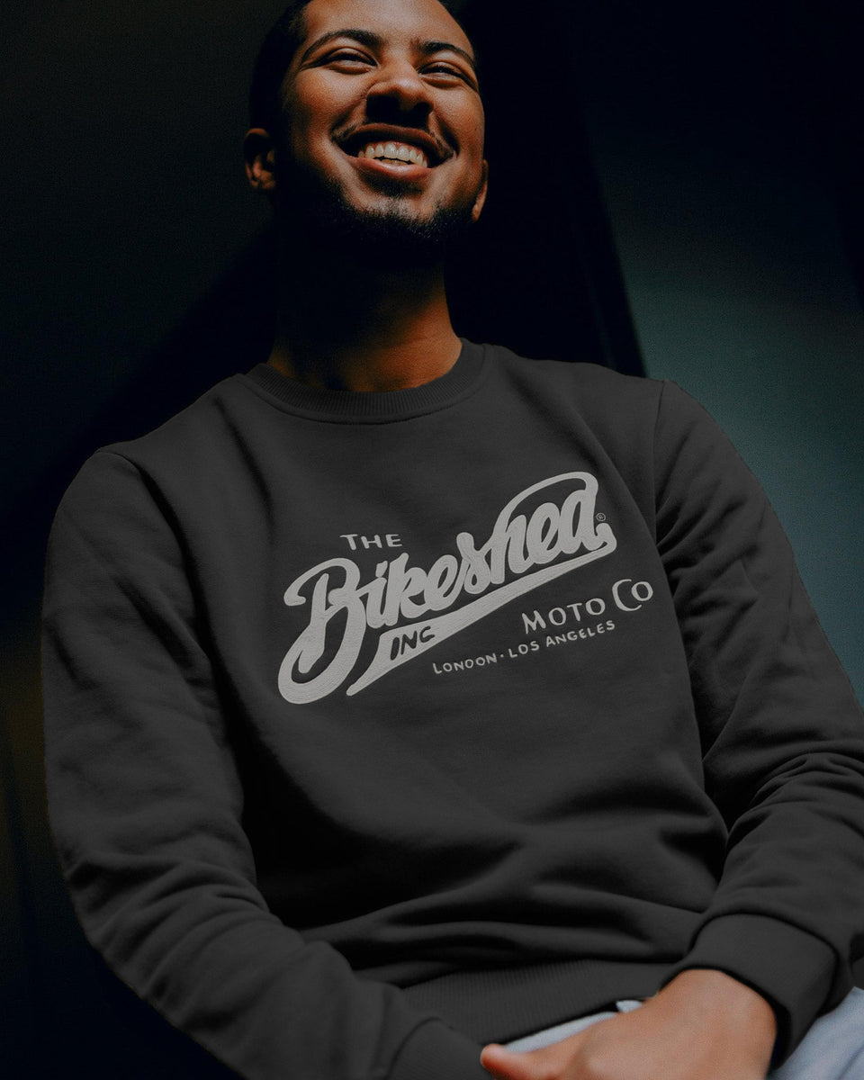 Person wearing a black sweatshirt with 'The Bikeshed Moto Co' logo on a dark background